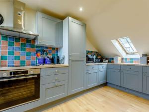 a large kitchen with blue cabinets and a window at 3 Bed in Braunton oc-86704 in Braunton +5 photos