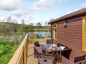 a deck with a table and chairs next to a lake at 2 Bed in South Brent oc-82871 in South Brent