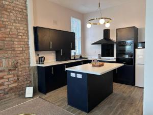 a kitchen with black cabinets and a brick wall at Spacious Victorian Apt Sleeps 5 Parking available in Nottingham