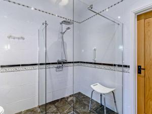 a glass shower with a stool in a bathroom at 1 Bed in Kilgetty oc-59667 in Yerbeston +16 photos