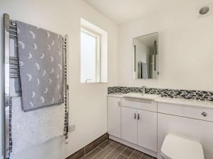 a white bathroom with a sink and a mirror at 4 Bed in Aberdovey oc-87586 in Aberdyfi +17 photos
