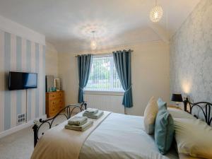 a bedroom with a large white bed with blue curtains at 4 Bed in Llandudno oc-75466 in Llandudno