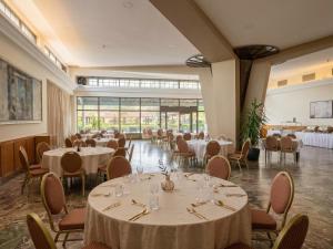 a dining room with tables and chairs and a large window at Hotel Bellevue in Skopje