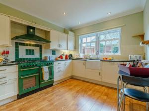 a large kitchen with white cabinets and green appliances at 3 Bed in Richmond oc-90578 in Catterick Bridge
