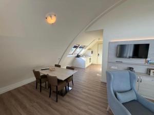 ein Wohnzimmer mit Tisch, Stühlen und Fernseher in der Unterkunft Hotel Rasch in Bergen aan Zee
