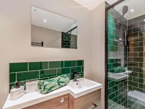a green tiled bathroom with a sink and a mirror at 2 Bed in Rhyl oc-94036 in Kinmel Bay +13 photos