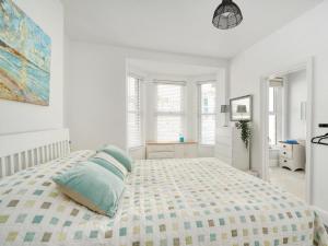 a white bedroom with a large bed with blue pillows at 5 Bed in Ilfracombe oc-89563 in Ilfracombe