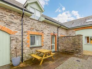 a wooden picnic table in front of a brick building at 2 Bed in Ilfracombe oc-rugga in Berrynarbor