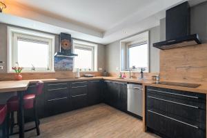 a kitchen with black cabinets and a table and windows at Guesthouse Eindeloos in 't Zand - North Holland in 't Zand