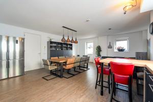 a kitchen and dining room with a table and red chairs at Guesthouse Eindeloos in 't Zand - North Holland in 't Zand