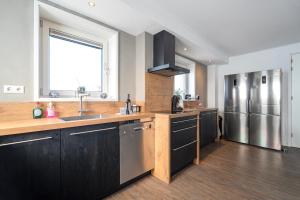 a kitchen with black cabinets and a stainless steel refrigerator at Guesthouse Eindeloos in 't Zand - North Holland in 't Zand