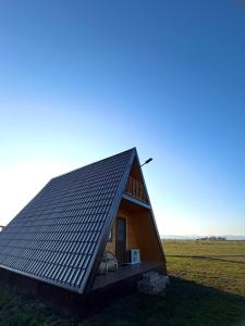a small house with a tin roof on a field at Șoaptele Naturii A-frame in Buzău