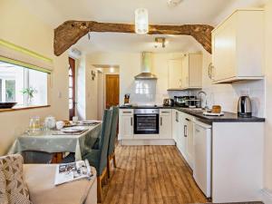 a kitchen with white cabinets and a table with chairs at 1 Bed in Ilfracombe oc-parsc in Berrynarbor