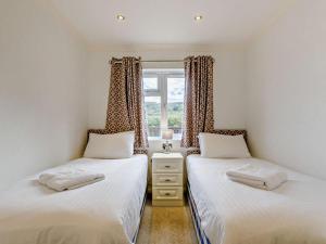 two twin beds in a room with a window at 2 Bed in Okehampton oc-74242 in Okehampton