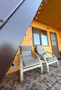 two chairs and a cat sitting on a patio at Șoaptele Naturii A-frame in Buzău