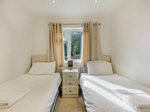 two twin beds in a bedroom with a window at 2 Bed in Okehampton oc-85432 in Okehampton