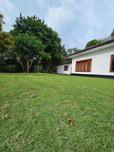 a large grassy yard with a white building at Alpha bungalow in Kandy +10 photos