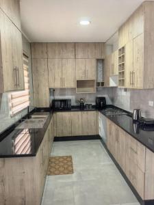a large kitchen with wooden cabinets and black counter tops at Nkambo Apartments in Kitwe