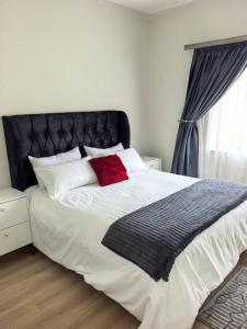 a bedroom with a large bed with a red pillow at Nkambo Apartments in Kitwe