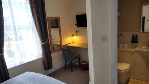 a room with a bed and a desk with a mirror at Geckos Rest in Newquay