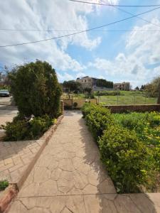 a walkway with bushes and a house in the background at Sea Nest Studio 1 in Agia Ermioni