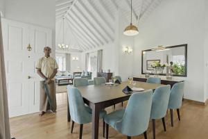 a man standing in a dining room with a table and chairs at Aadya Tea Bungalows by Aahaasa in Hatton