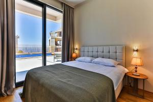 a bedroom with a bed and a large window at Poljana Olive Homes Pool Residences in Rijeka Reževići +62 photos
