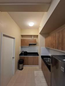 a kitchen with wooden cabinets and a black counter top at Avida Storeys 2 7th Floor in Iloilo City