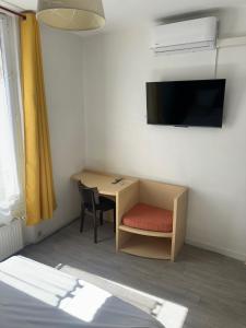 a room with a desk with a chair and a tv at Hôtel Trianon in Juan-les-Pins