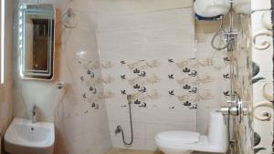a bathroom with a toilet and a shower with butterflies on the wall at Pradhan Hotel Mirik Lake Side in Mirik +25 photos