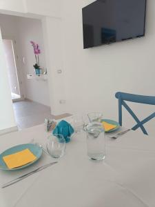 a table with glasses and plates and a television at B&B Benefici in Maruggio