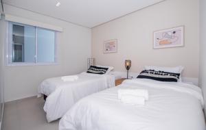 two white beds in a white room with a window at Cityscape Views - New 2BR Retreat in Asunción +14 photos