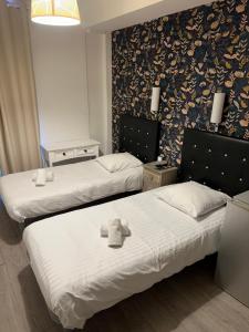 two beds in a hotel room with a teddy bear on them at Hôtel Trianon in Juan-les-Pins