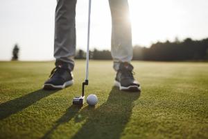 a golfer is standing next to a golf ball at Hotel Grad Otočec - Relais Chateaux in Otočec