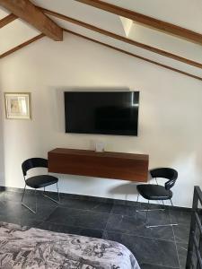 a room with two chairs and a television on a wall at Amorino Apartman Studio in Opatija