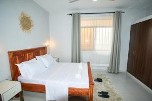 a bedroom with a large white bed and a window at Diani Dream stays 2 in Diani Beach