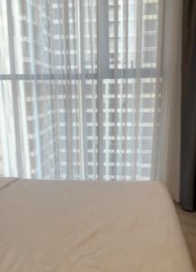 a bedroom with a bed and a window with white curtains at KSWL Residence in Long Bình