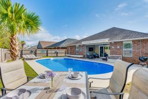 a patio with a table and chairs next to a pool at Private Pool + Patio: Pensacola Family Home! in Perdido Key