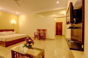 a bedroom with a bed and a table and chairs at Royal Garden Brindavan Resort in Hosa Kannambādi
