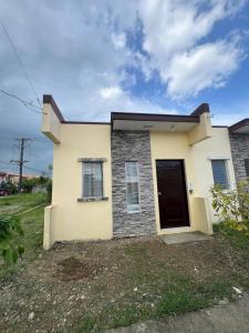 a small white house with a black door at ALCA Homestay in Palo