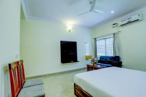 a white bedroom with a bed and a television at Royal Garden Brindavan Resort in Hosa Kannambādi +9 photos