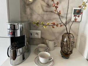 a counter with a coffee maker and a vase with cups at TUGENDHAT Boutique Suite in Komárov