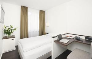 a hotel room with a white bed and white walls at Eden Hotel Wolff in Munich