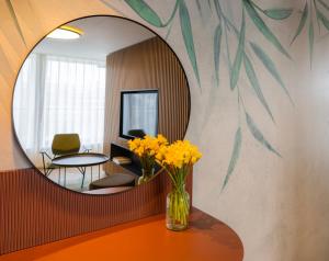 a mirror on a wall with a vase of yellow flowers at Botel Marina in Prague