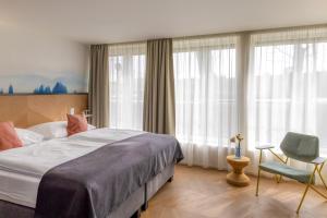 a bedroom with a bed and a chair and windows at Botel Marina in Prague