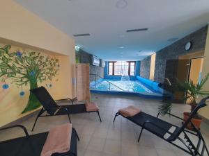 a room with chairs and a swimming pool in the background at Kúpeľný dom GERLACH in Vysoké Tatry