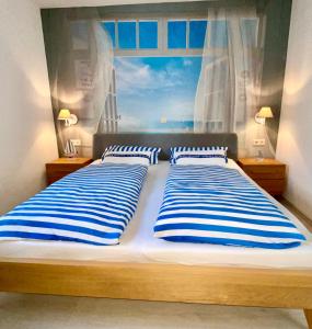 a bedroom with two beds with blue and white striped pillows at Ferienresidenz Seegarten Andrea - Seezugang und Schwimmbad in Bodman-Ludwigshafen +30 photos