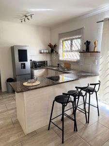 a kitchen with three bar stools and a counter at Immari stays in Swakopmund