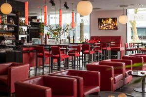 a restaurant with red chairs and a bar at ARCOTEL Rubin Hamburg in Hamburg