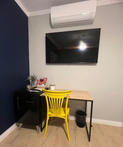 a yellow chair sitting next to a table with a television on the wall at Villa Catarina in Guarulhos